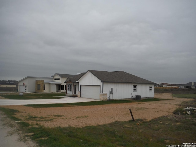 view of front of home with a garage, central AC, and concrete driveway