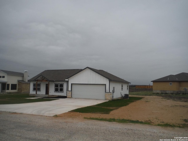 view of front of home with concrete driveway, central air condition unit, and an attached garage