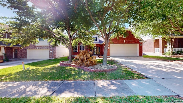 view of property hidden behind natural elements with a garage, a front yard, concrete driveway, and brick siding