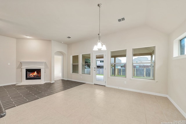 unfurnished living room with a chandelier, a lit fireplace, visible vents, and baseboards