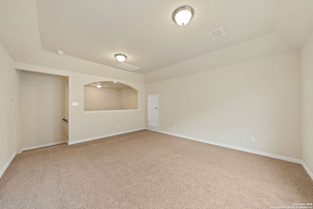 spare room featuring a textured ceiling, carpet flooring, visible vents, and baseboards