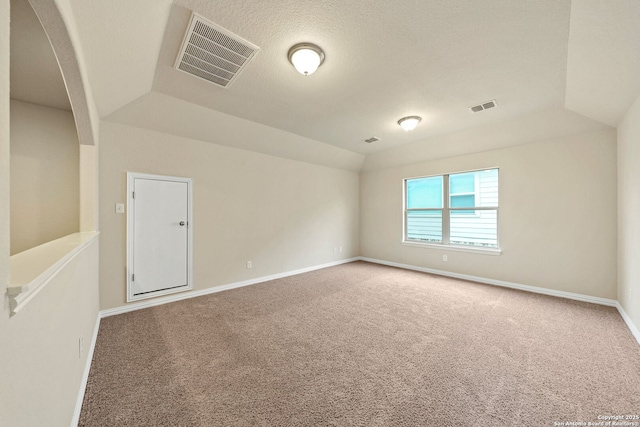 carpeted spare room with visible vents, vaulted ceiling, a textured ceiling, and baseboards