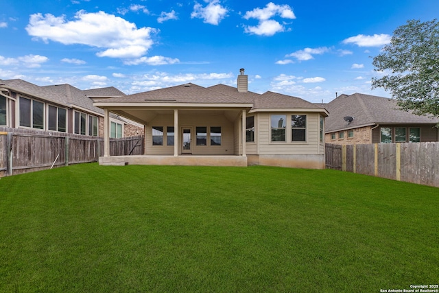 rear view of house with a yard, a chimney, a patio, a shingled roof, and a fenced backyard