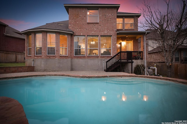 pool at dusk with fence and a fenced in pool