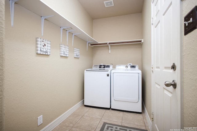 laundry room featuring laundry area, light tile patterned floors, baseboards, visible vents, and washing machine and clothes dryer