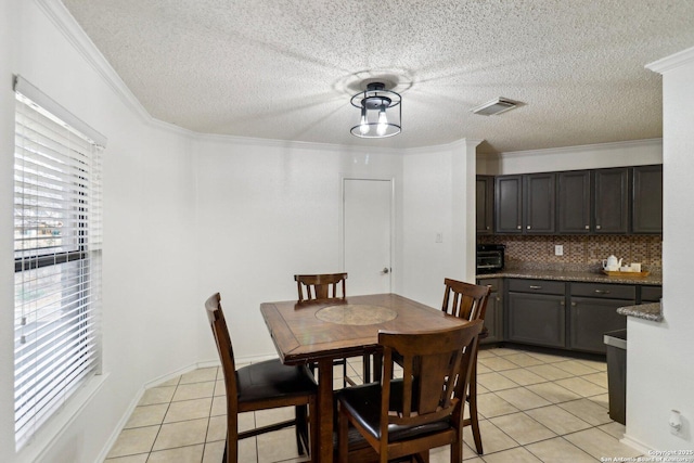 dining room featuring light tile patterned floors, ornamental molding, a textured ceiling, and visible vents