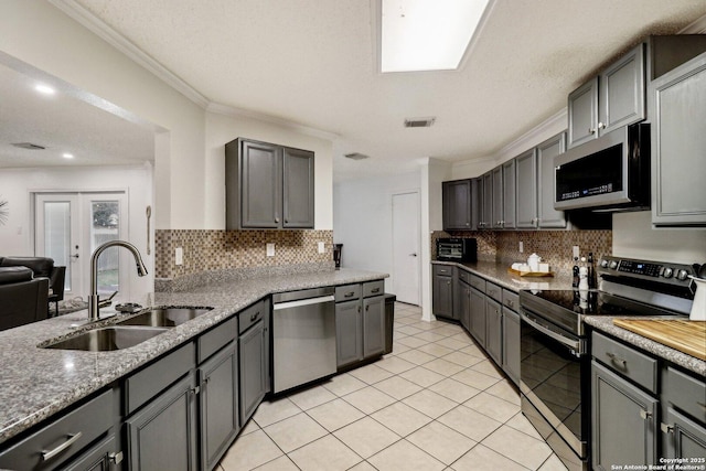 kitchen featuring light tile patterned floors, stainless steel appliances, a sink, visible vents, and crown molding