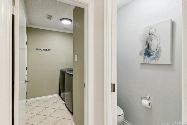 laundry area featuring a textured ceiling, light tile patterned floors, laundry area, visible vents, and washer and clothes dryer