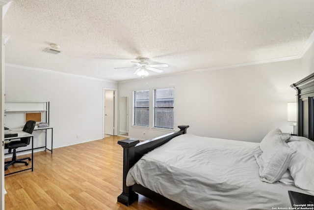 bedroom featuring a textured ceiling, light wood finished floors, visible vents, and crown molding