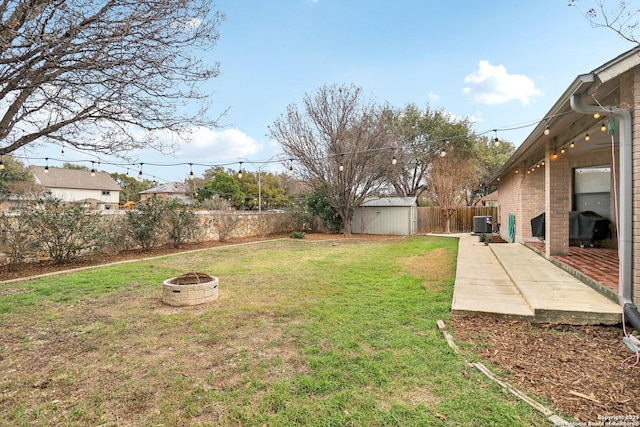 view of yard featuring an outbuilding, a patio, a storage shed, a fenced backyard, and a fire pit