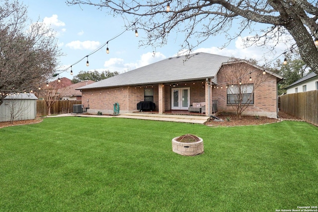 back of house featuring an outdoor fire pit, a fenced backyard, cooling unit, brick siding, and french doors