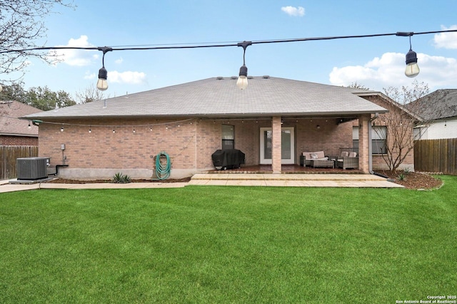 rear view of property featuring brick siding, a lawn, cooling unit, and fence