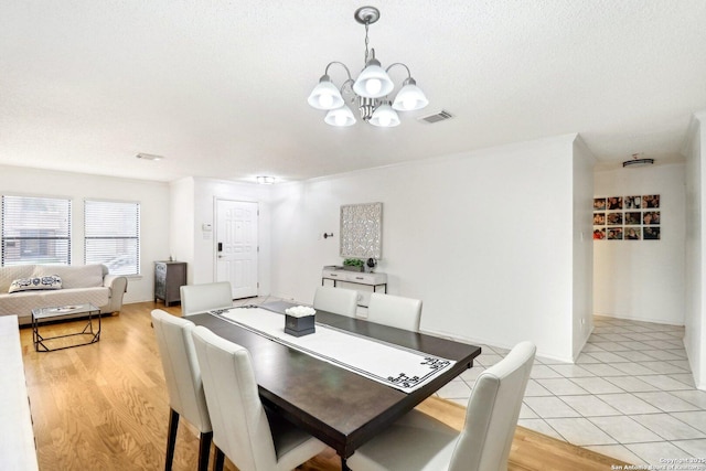 dining area with visible vents, light wood-style flooring, and an inviting chandelier