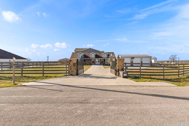 view of street with concrete driveway, a gate, a rural view, and a gated entry