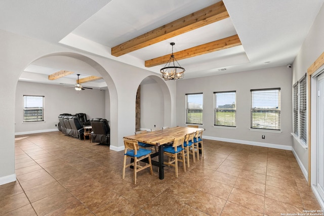 tiled dining room with a tray ceiling, arched walkways, baseboards, and beam ceiling