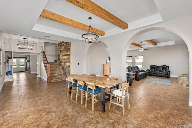 tiled dining area featuring stairway, visible vents, a raised ceiling, beamed ceiling, and ceiling fan with notable chandelier