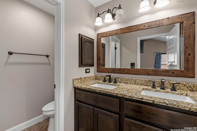 full bath with double vanity, tile patterned floors, toilet, and a sink