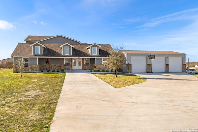 view of front of home featuring stone siding, a detached garage, french doors, a front yard, and a shingled roof