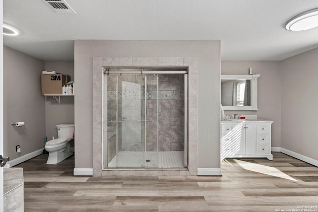 bathroom featuring visible vents, toilet, a stall shower, wood finished floors, and baseboards