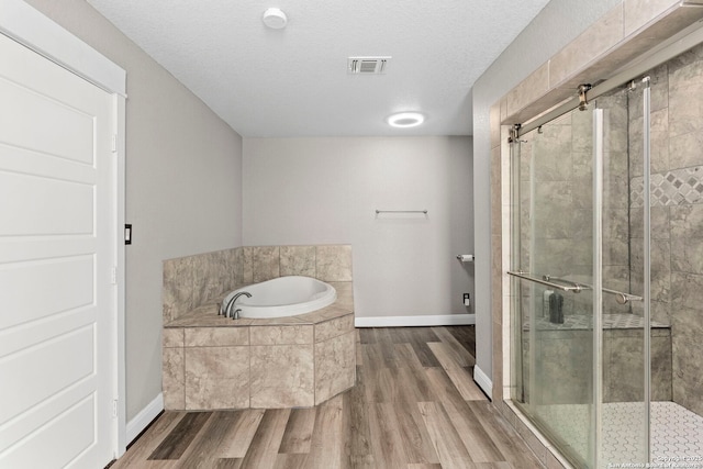 bathroom with a garden tub, wood finished floors, a stall shower, and visible vents