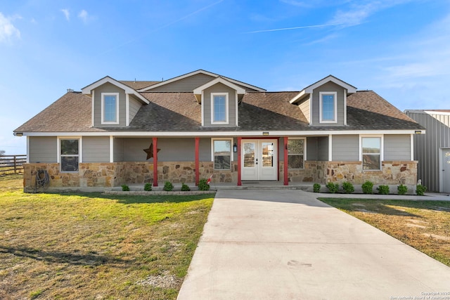 view of front of home with a front yard, fence, a shingled roof, french doors, and stone siding