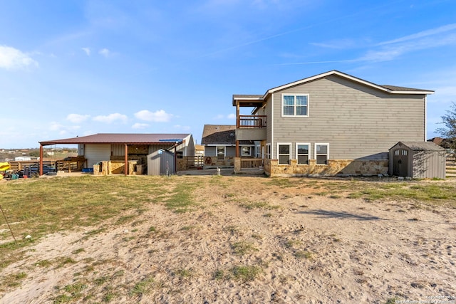 rear view of property with a balcony, a storage unit, and an outdoor structure