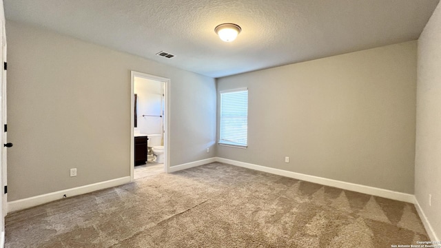 carpeted spare room with a textured ceiling, visible vents, and baseboards