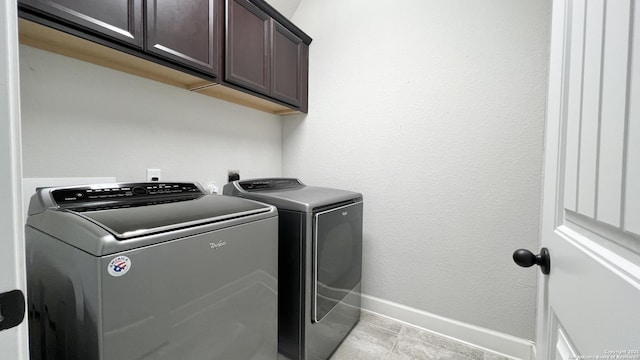 laundry area with separate washer and dryer, cabinet space, and baseboards