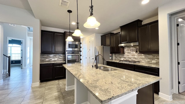 kitchen featuring a center island with sink, stainless steel appliances, visible vents, a sink, and under cabinet range hood