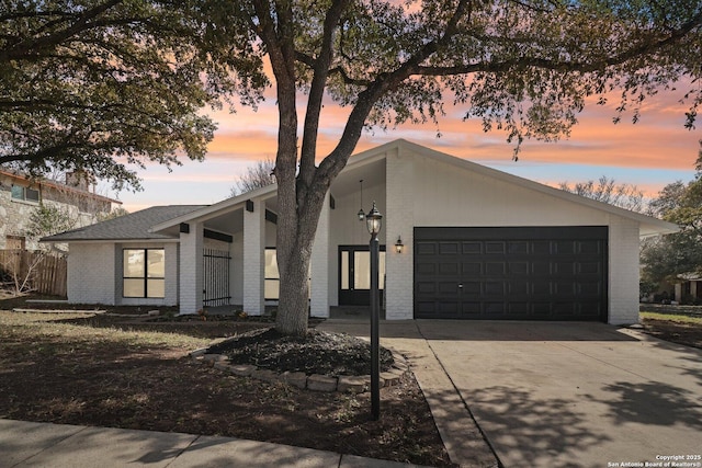 mid-century modern home with a garage, brick siding, and driveway