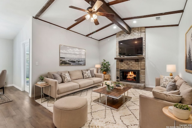 living room featuring vaulted ceiling with beams, a fireplace, wood finished floors, visible vents, and baseboards