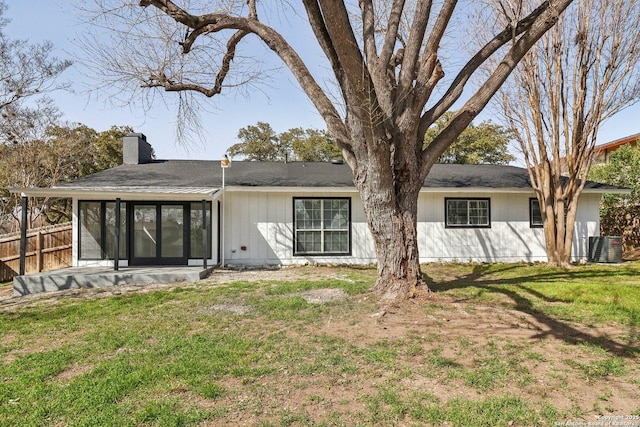 rear view of property featuring a sunroom, a chimney, fence, and a lawn