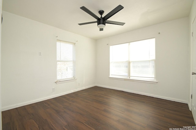 empty room featuring ceiling fan, dark wood-style flooring, and baseboards