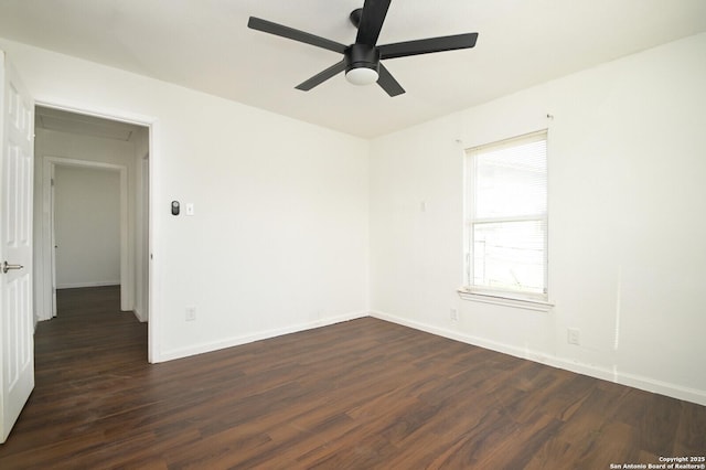 spare room featuring dark wood-style floors, ceiling fan, and baseboards