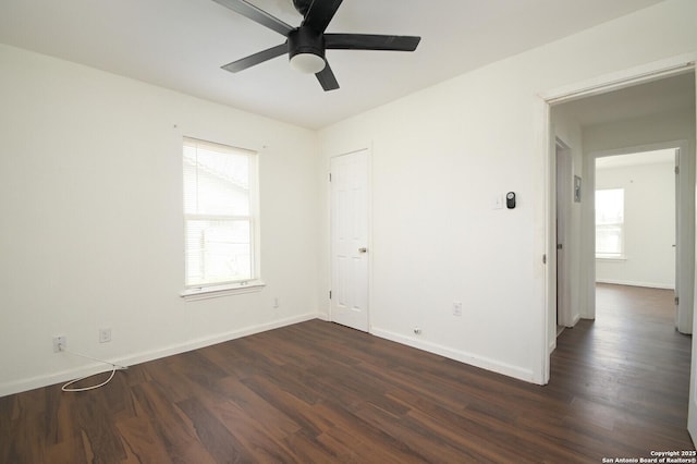 spare room featuring a ceiling fan, baseboards, and dark wood-type flooring