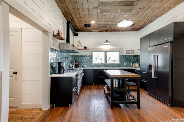 kitchen featuring hardwood / wood-style flooring, high quality appliances, dark cabinetry, open shelves, and a sink