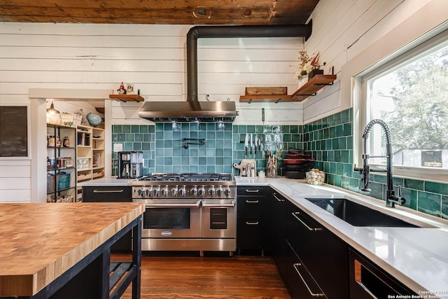 kitchen with dark wood-type flooring, dark cabinetry, double oven range, wooden counters, and a sink