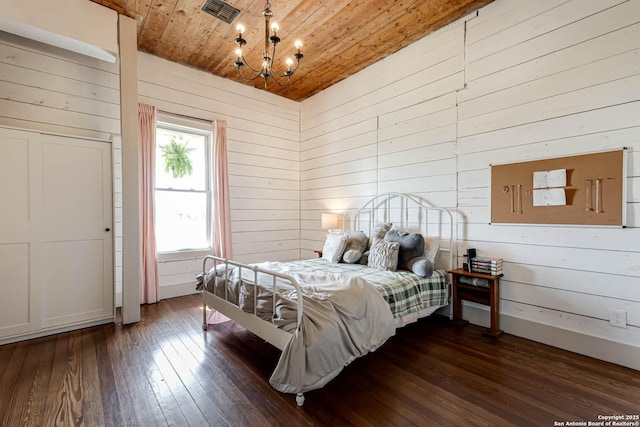 bedroom with baseboards, visible vents, dark wood finished floors, wooden ceiling, and a notable chandelier