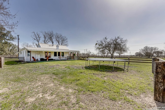 view of front of property with metal roof, a standing seam roof, a trampoline, board and batten siding, and a front yard