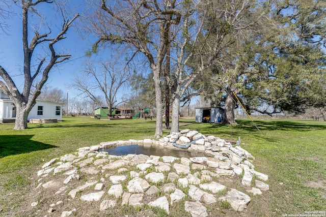 view of yard with a storage unit, a playground, and an outdoor structure