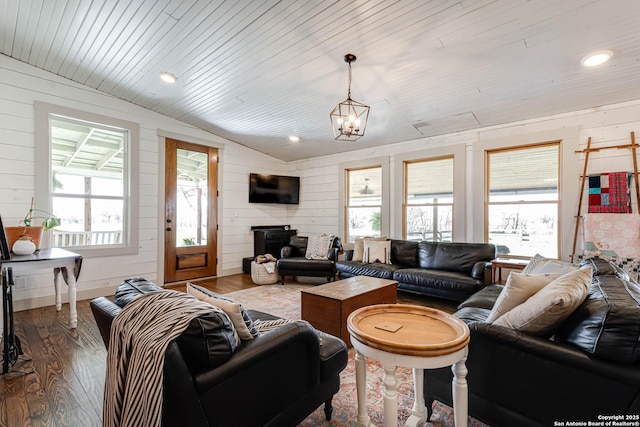 living room featuring lofted ceiling, a healthy amount of sunlight, wooden walls, and wood finished floors