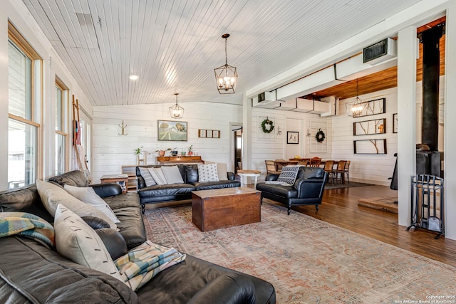 living room with wooden walls, lofted ceiling, wood ceiling, wood finished floors, and a notable chandelier