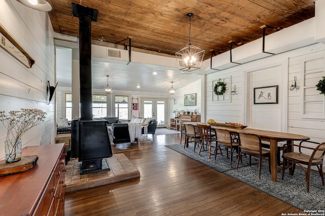 dining room with visible vents, wooden ceiling, dark wood-style flooring, a wood stove, and french doors