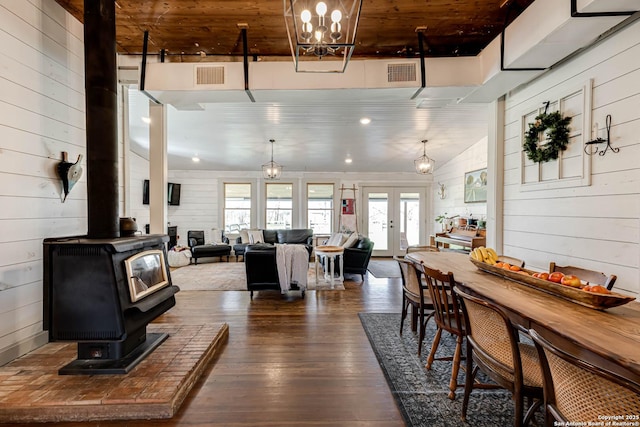 dining room featuring visible vents, french doors, dark wood-style floors, and a wood stove