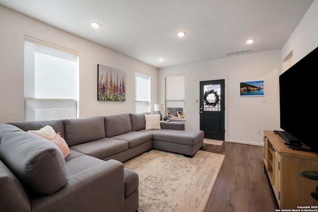 living room featuring baseboards, dark wood-type flooring, visible vents, and recessed lighting