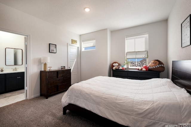 bedroom with a sink, connected bathroom, and light colored carpet