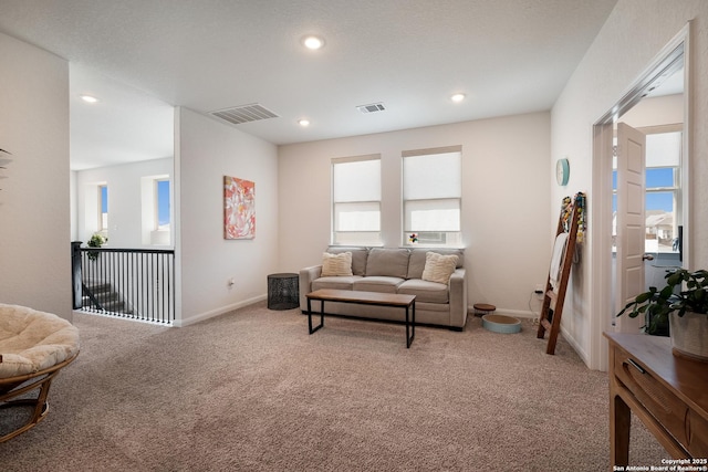 living room with recessed lighting, visible vents, and light colored carpet