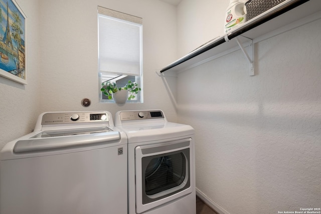 washroom with laundry area, a textured wall, and separate washer and dryer