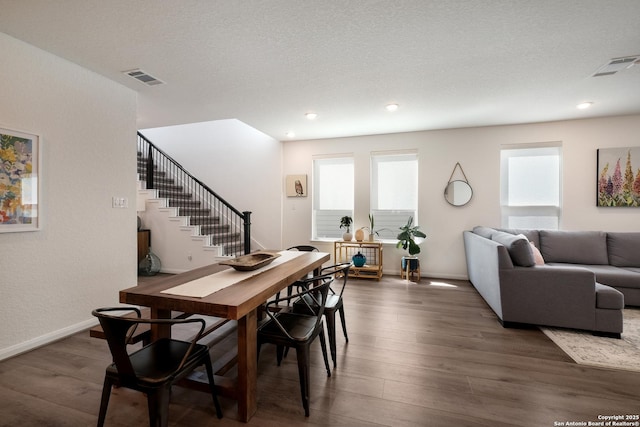 dining area with stairway, visible vents, a wealth of natural light, and wood finished floors