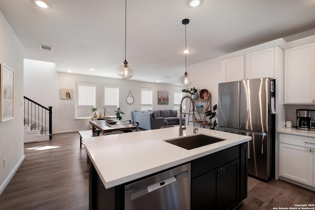 kitchen featuring a center island with sink, visible vents, stainless steel appliances, light countertops, and a sink